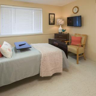 A cozy bedroom featuring a neatly made bed, a comfortable chair, and decorative elements.
