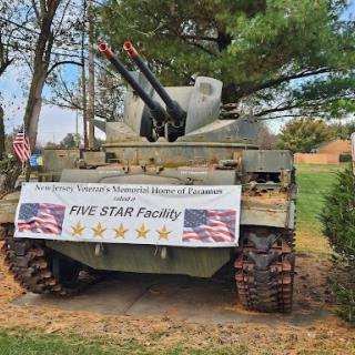 A military tank on display, honoring veterans with a banner promoting the 'Five Star Project.'