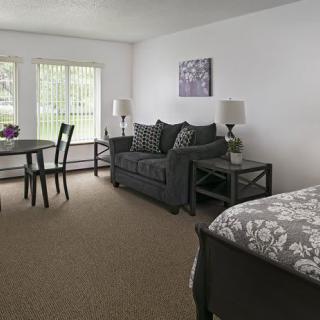A cozy studio apartment with a sofa, dining area, and bed.