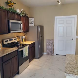 A modern kitchen featuring stainless steel appliances, dark wood cabinets, and a granite countertop.
