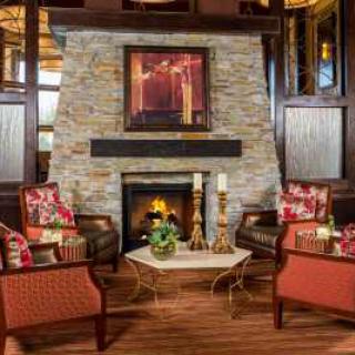 A cozy living room with a stone fireplace, surrounded by comfortable chairs and decorative accents.