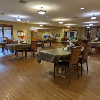 A spacious and well-lit dining area featuring several tables and chairs, perfect for community gatherings.