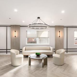 A modern living room with minimalist decor and neutral color tones, featuring a chandelier and comfortable seating.