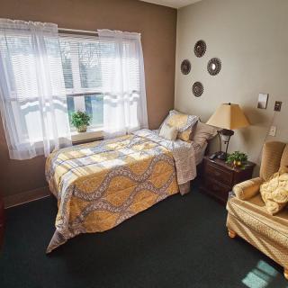 A cozy bedroom with a single bed, sunlight streaming through the window, and warm decor.