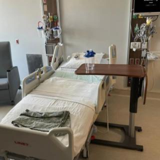 A hospital room featuring a bed, medical equipment, and a bedside table.