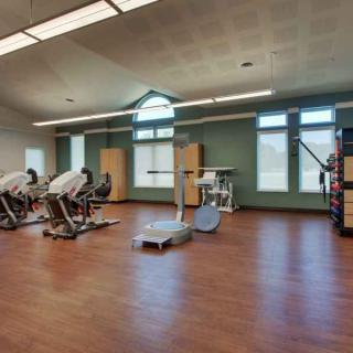 A spacious gym with modern exercise equipment and wooden flooring.