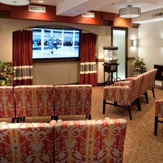 A cozy theater room with patterned seating, a large television screen, and warm lighting.