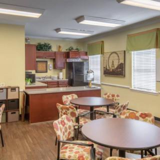 A cozy kitchen and dining area with round tables, patterned chairs, and ample natural light.