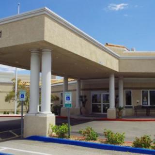 A building entrance with columns and a parking lot in front.