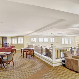 A spacious lounge area with tables, chairs, and large windows.