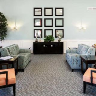 A cozy living room with patterned sofas, wall art, and a decorative plant.