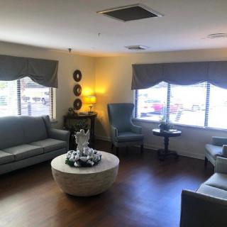 A cozy living room featuring sofas, large windows, and a central coffee table.