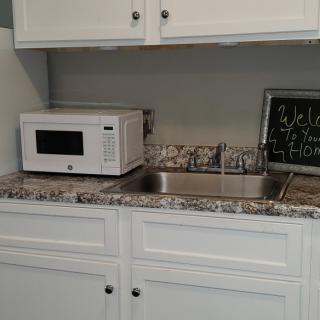 A kitchen area with a microwave and sink on a granite countertop.