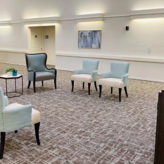 A minimalist seating area with a few chairs arranged on a patterned carpet.