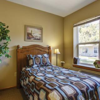 A cozy bedroom with a single bed and a large window.