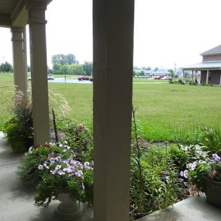 A peaceful view from the porch, showcasing a vibrant garden and expansive green lawn.