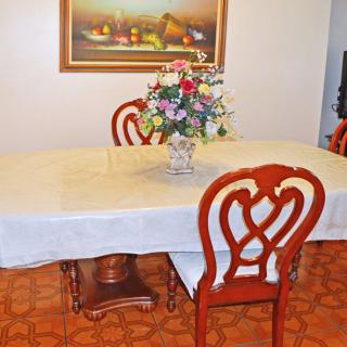 A dining room setup featuring a table with a floral centerpiece and elegant wooden chairs.