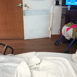 A view from a hospital room featuring a patient bed, door, and some furnishings.