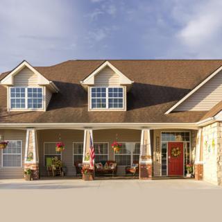 A suburban residential house with a large porch and a red door.