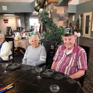 Seniors enjoying a festive gathering with party hats at a decorated venue.