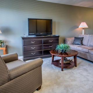 A cozy living room featuring a sofa, armchair, coffee table, and television.