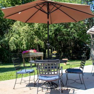 A cozy outdoor patio setup with a table, chairs, and a large umbrella for shade.
