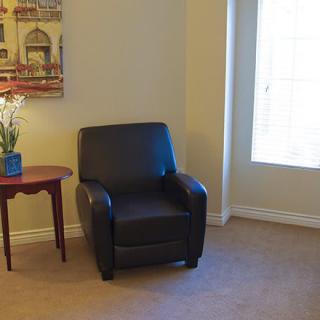 A cozy living room corner featuring a leather armchair next to a small side table and a window.
