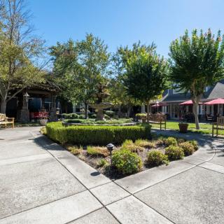 A serene courtyard with well-maintained gardens and outdoor seating under a clear blue sky.