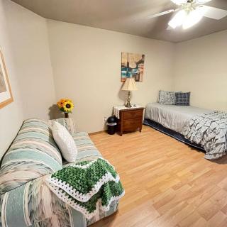 A cozy bedroom with a single bed and sofa, featuring wooden flooring and simple decor.