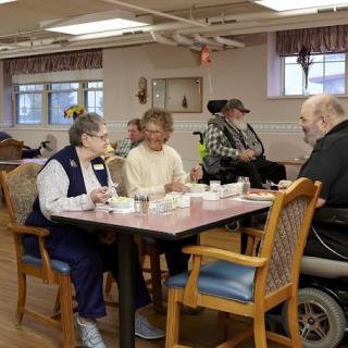 Elderly individuals dining together in a retirement home setting.