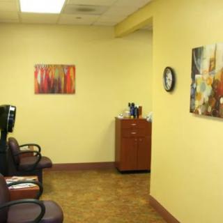 A view of a waiting room with chairs, artwork on the walls, and a clock.