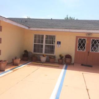 A small house with a driveway, windows, doors, and potted plants.
