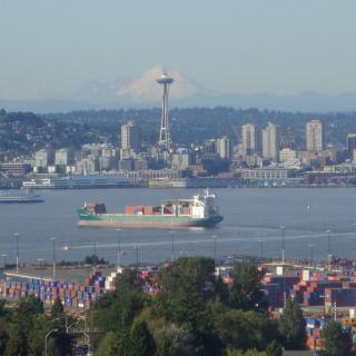 View of Seattle skyline with the Space Needle and a cargo ship in the harbor.