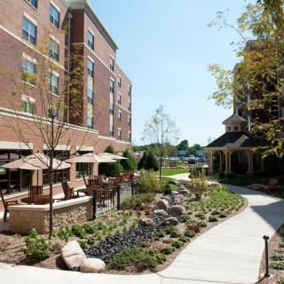 A well-landscaped outdoor area with seating next to a brick hotel building.