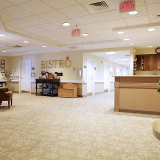 A cozy bistro with a reception area and seating in a carpeted hallway.