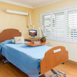 A clean and well-organized hospital room with a single bed and medical equipment.