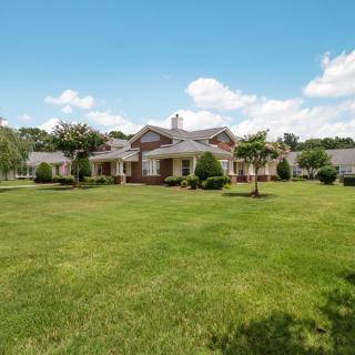 A large house with a spacious green lawn under a clear blue sky.