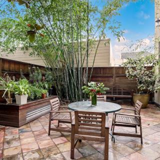 A cozy patio area with wooden furniture surrounded by lush plants.