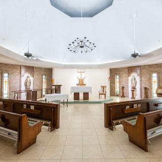 A serene interior of a church featuring wooden pews and a central altar.
