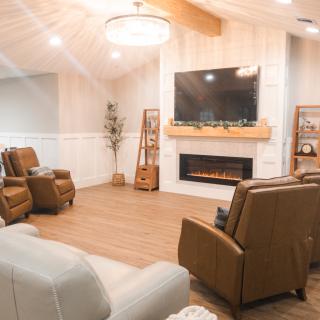 A modern and cozy living room with comfortable seating, a fireplace, and a large television.