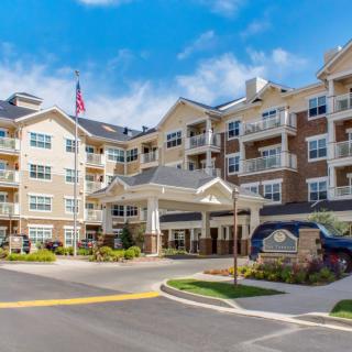 A modern residential building with balconies and well-maintained landscaping under a blue sky.