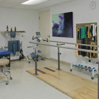 A rehabilitation room equipped with parallel bars and exercise equipment for physical therapy sessions.