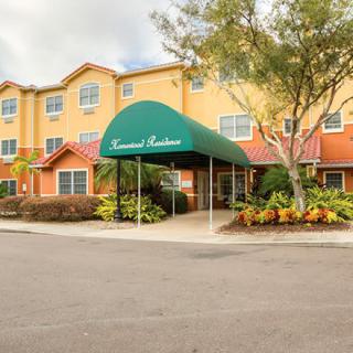 A hotel entrance with a green awning and surrounding foliage.