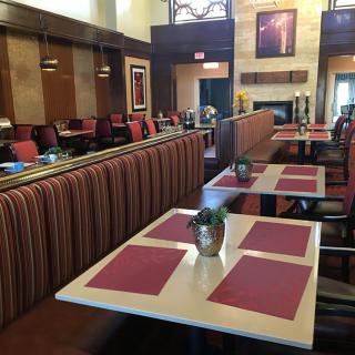 A cozy restaurant interior with neatly arranged tables and chairs, featuring red placemats and tasteful decor.
