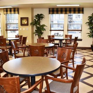 An empty dining area with round tables and wooden chairs in a well-lit room.