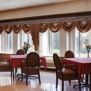 A well-lit dining area with tables and chairs, adorned with elegant curtains and floral centerpieces.