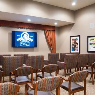 A small theater room with arranged seating and a screen displaying a logo.