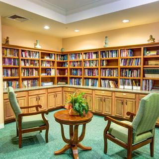 A cozy library corner with bookshelves, two chairs, and a small round table.