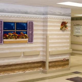 A decorated corridor wall designed to look like the exterior of a house with a window and flowers.