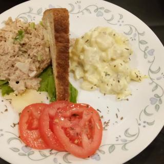 A plate with tuna salad, egg salad, toasted bread, and tomato slices.